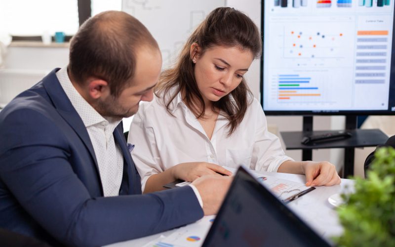 Colleagues of startup business discussing looking at documents in company board brainstorming conference room checking graphs and charts. Financial analysis during briefing.